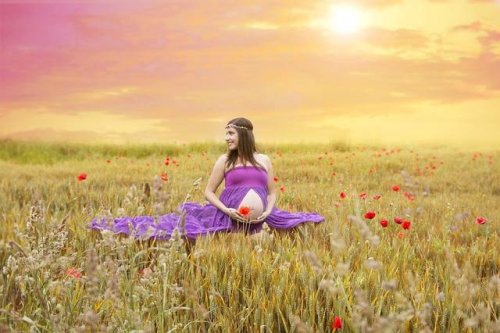 Pregnant woman in a sunny field with flowers
