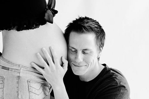 Father hugging pregnant woman's belly