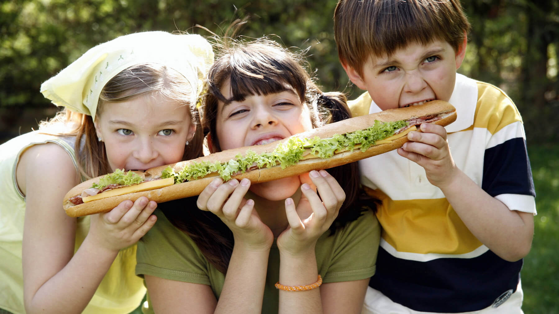 Three children sharing a sandwich