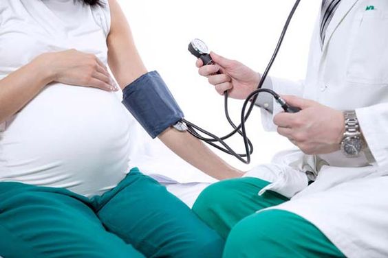 Pregnant woman getting her blood pressure checked with a doctor