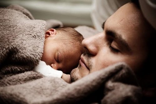 father sleeping with newborn