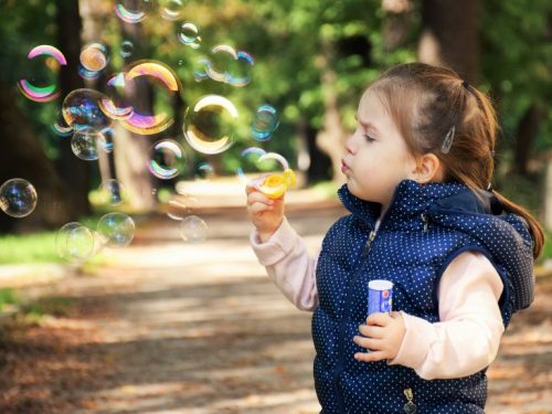 girl blowing bubbles in the park