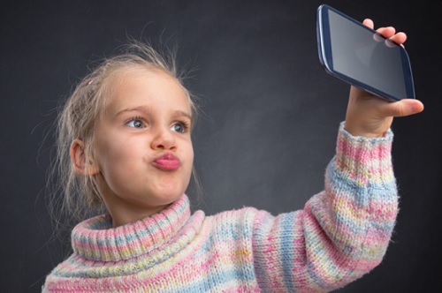 child holding cell phone taking selfie