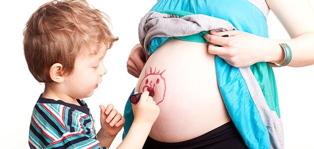 Boy drawing on pregnant mom's belly