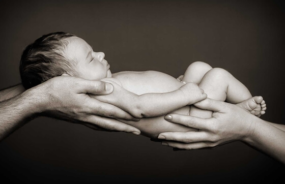 newborn baby being held by first-time parents