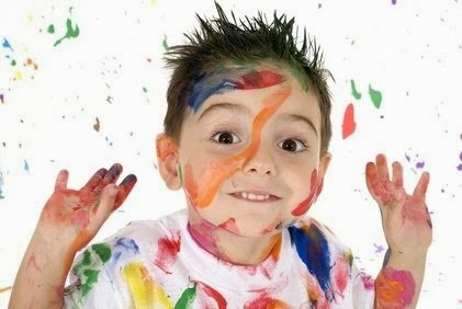little boy smiling and covered in paint