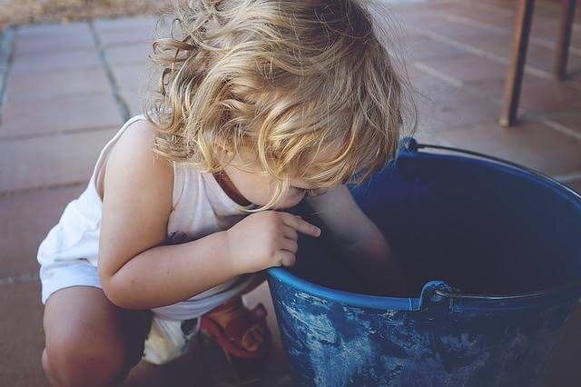 child reaching into a blue bucket