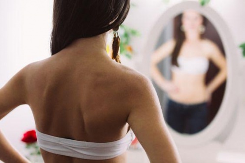 postpartum recover woman looking in the mirror
