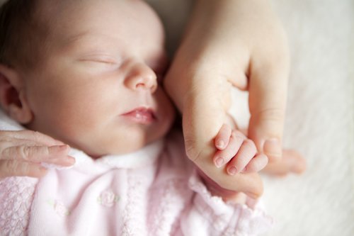 newborn baby and mother holding hands