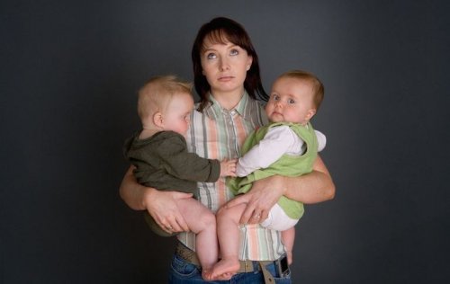 tired mother holding two babies