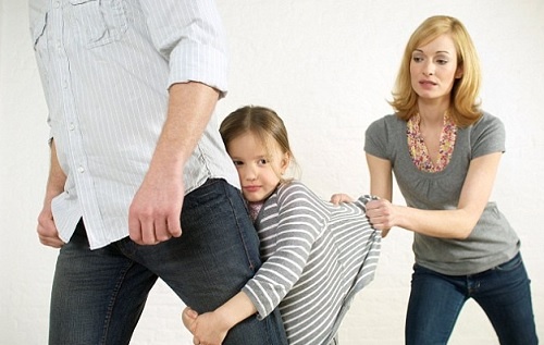 girl clinging to dad's leg