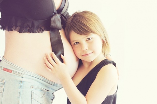 girl resting her head on her mom's pregnant belly