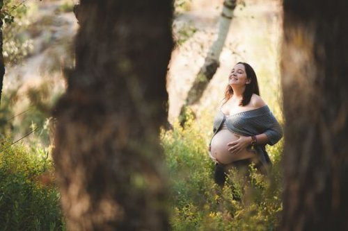 pregnant woman smiling in the sun in the park