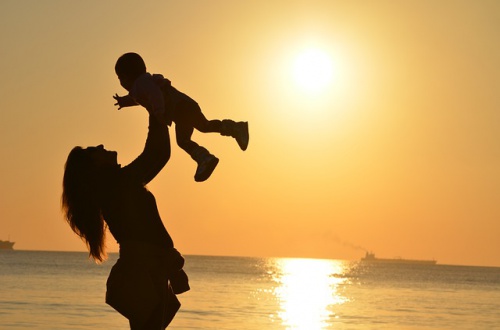 silhouette of mom holding baby up in the air
