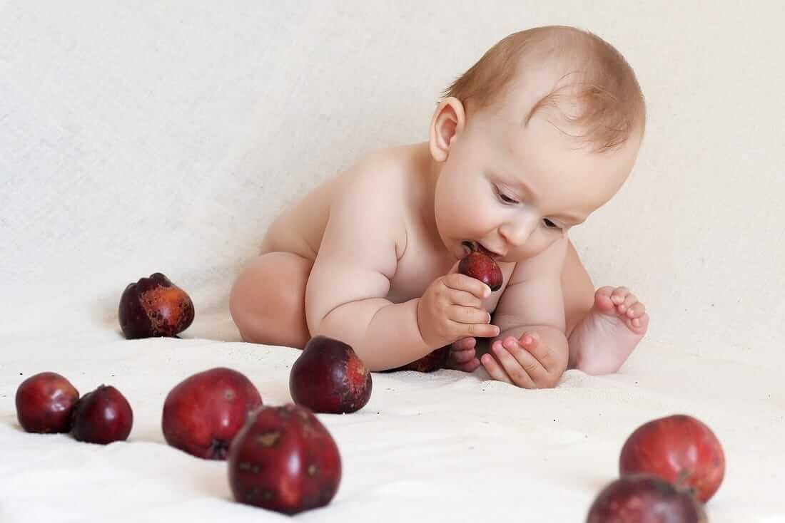 Baby som äter plommon