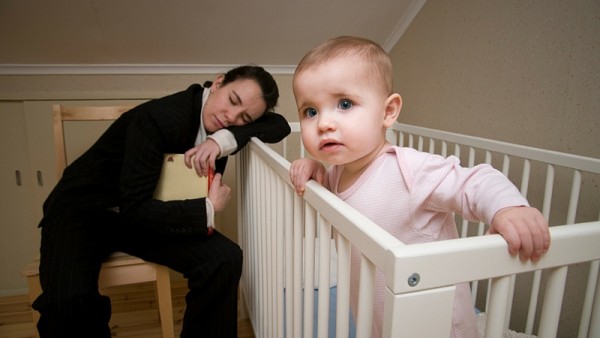 sleeping mother beside baby's crib