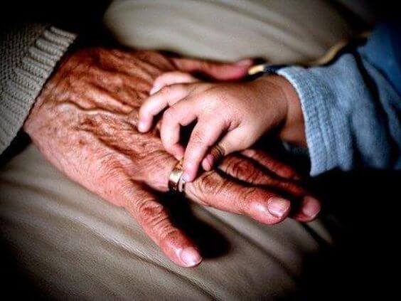 A small child's hand resting on an old person's hand.