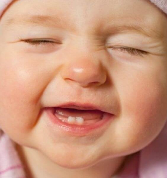 Tecken på att ditt barns första tand håller på att komma fram