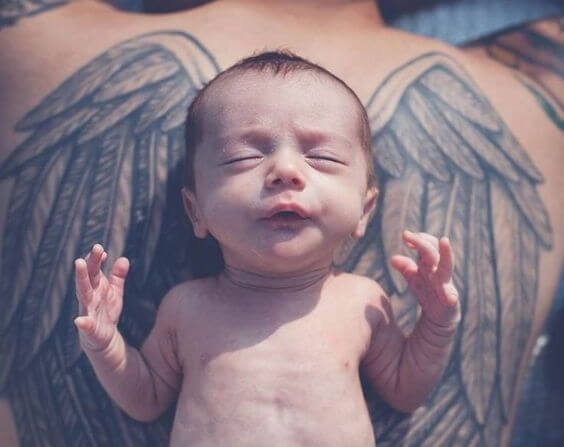 bebis ovanpå tatuering av vingar