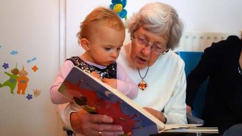 A grandmother reading to her baby granddaughter.