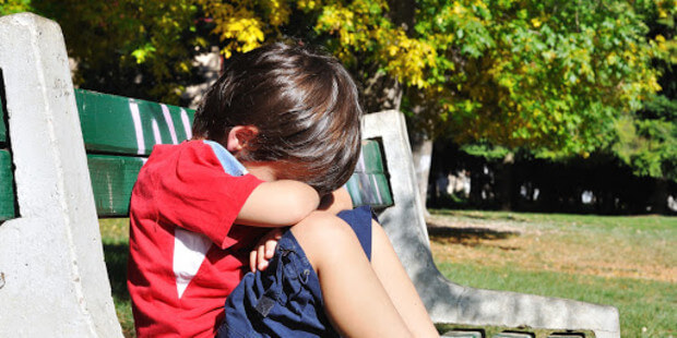dreng på bænk med hovedet i skødet