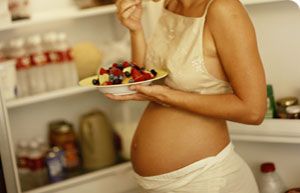 Pregnant woman eating berries with yogurt.