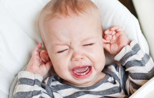 lille baby der græder og holder sig i ørerne