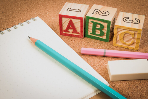 blyant, papir og blokke med bogstaver