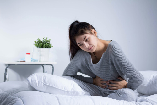 kvinde i seng med mavesmerter
