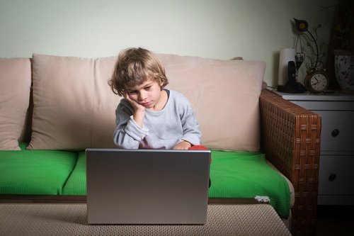 barn i sofa der ser noget på computer