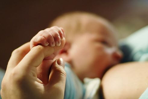 ammende baby der holder om sin mors finger