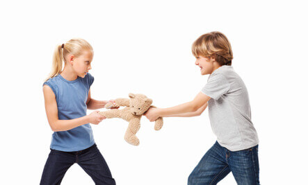 en dreng og pige der kæmper om en bamse