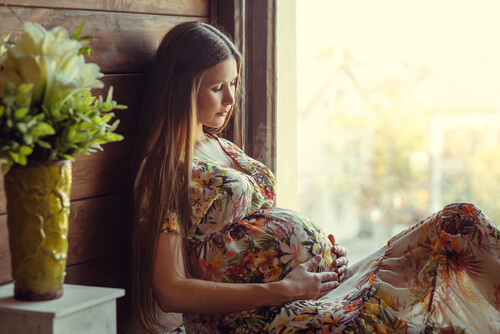 gravid kvinde i kjole der holder om sin mave