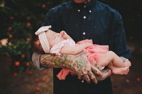 lille baby liggende i tatoverede arme