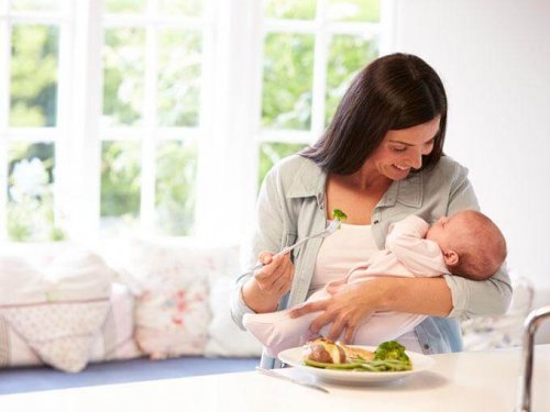 mor der spiser mens hun holder sin baby på armen