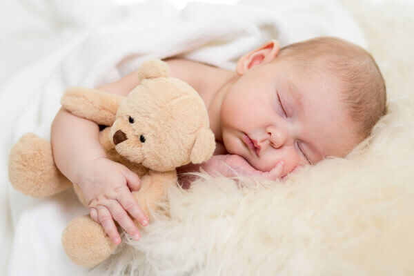 baby der sover med en bamse