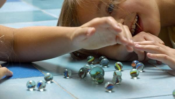 børn der leger med små glaskugler