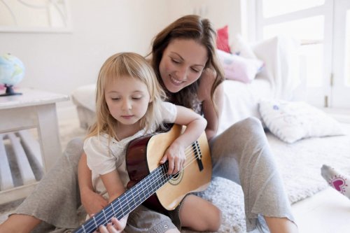 mor og datter der øver på en guitar