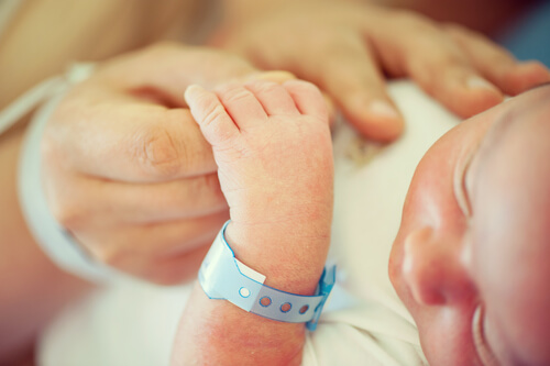 nyfødt baby med hospitalsarmbånd der holder om finger