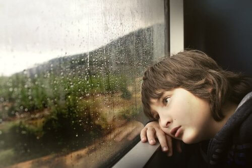 dreng der kigger ud på regn gennem vindue