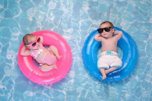 små babyer med solbriller i baderinge i en pool