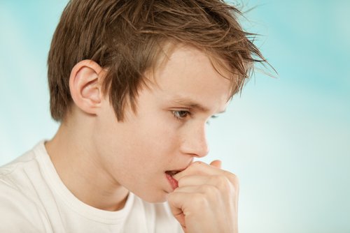 A boy biting his nails.