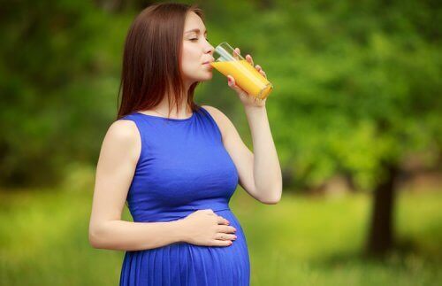 gravid kvinde der drikker juice udenfor