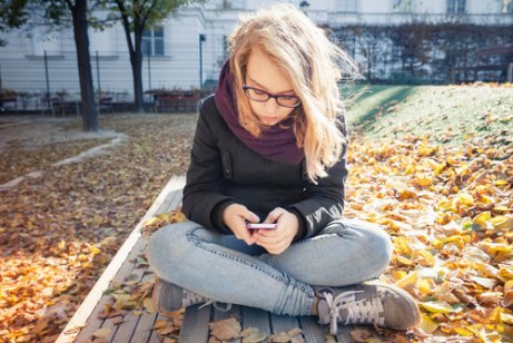 teenager med sin mobil på en bænk udenfor