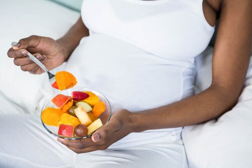 pregnant woman eating a bowl of fruit