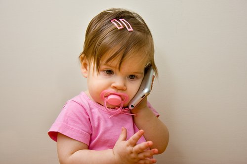 lille pige med sut der har mobil ved øret
