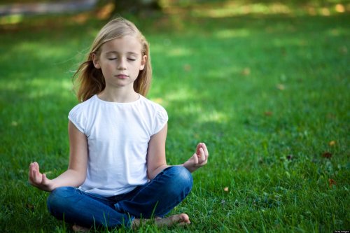 pige der sidder på græsplæne og mediterer