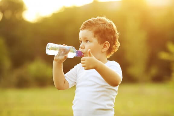 Barn drikker vand af flaske