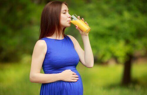 pregnant woman drinking orange juice outside