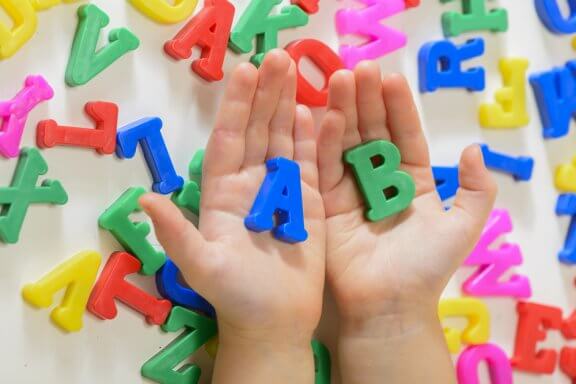 A child holding alphabet magnets.